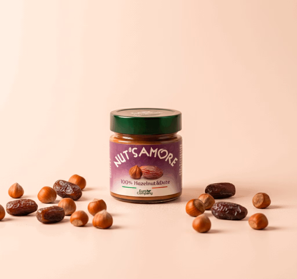 Jar of Nut's Amore 100% Hazelnut & Date spread surrounded by hazelnuts and whole dates